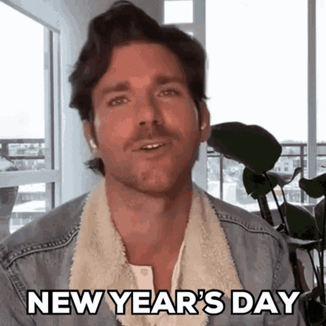 a man in a denim jacket is talking on a video call and says new year 's day .