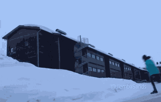 a person is walking in the snow in front of a building with stairs .