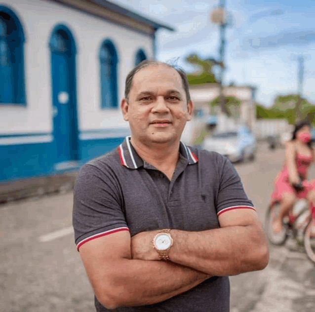 a man stands with his arms crossed in front of a building