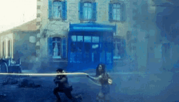 a man and a woman are walking down a street in front of a building with blue shutters .