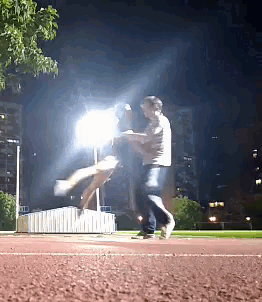 a man is holding a woman in his arms in a park at night