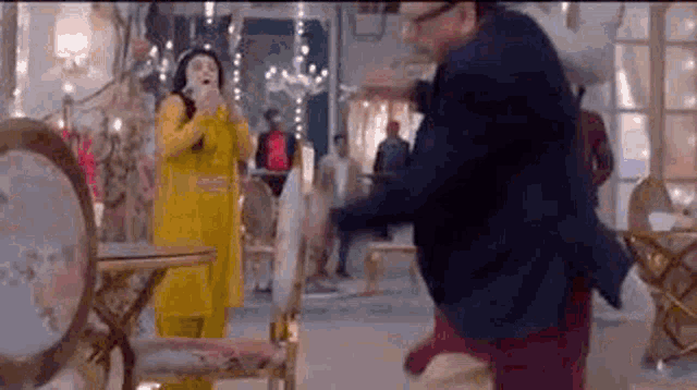 a man and a woman are dancing in a room with chairs and tables .