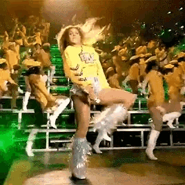 a woman wearing a yellow shirt that says ' aa ' on it is dancing on a stage