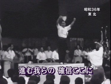 a man stands on a stage in front of a crowd with a sign that says 36 on it