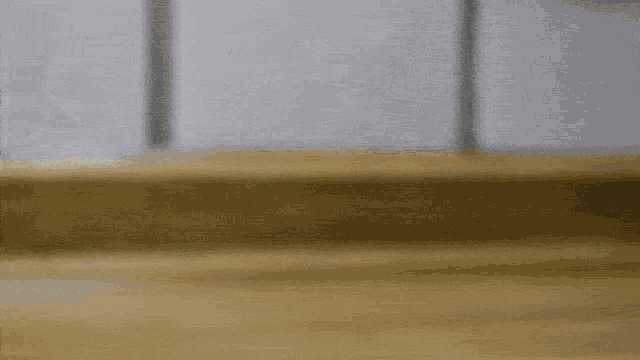 a blurred image of a wooden floor with a white wall behind it