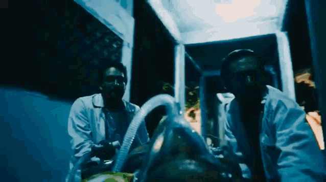 a man in a lab coat is standing next to a man with an oxygen mask on his face
