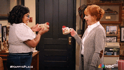 two women are standing in front of a door with a nbc logo on the bottom