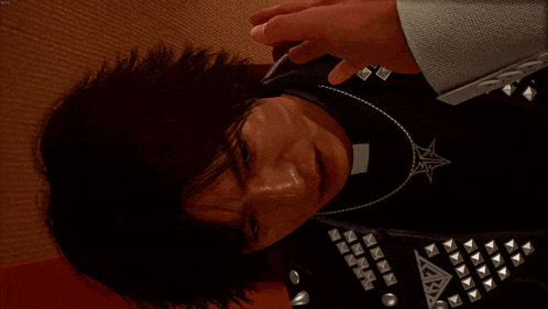 a man wearing a leather jacket with studs on it is being slapped