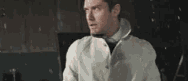 a man in a white coat and tie is standing in front of a computer .