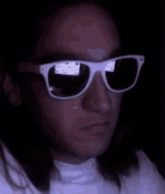 a close up of a man wearing sunglasses in the dark .