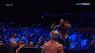 a wrestler is laying on the ground in front of a sign that says dynamite
