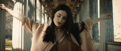 a woman is dancing in a hallway with her arms outstretched in front of columns .