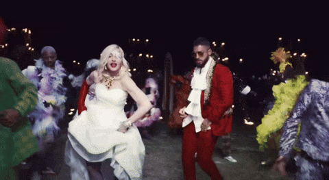 a woman in a white dress and a man in a red suit are dancing together