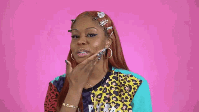 a woman with long red hair is wearing a leopard print shirt and earrings and is touching her hair .