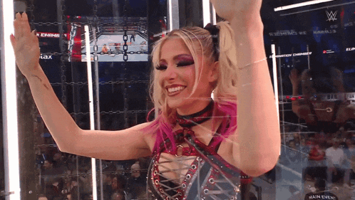 a woman with pink hair is smiling with her arms in the air in front of a main event sign