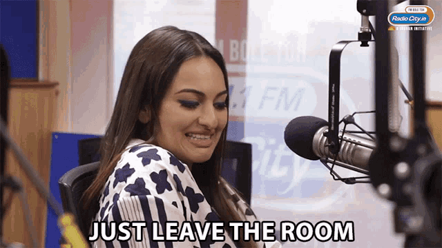 a woman in front of a microphone with the words just leave the room below her