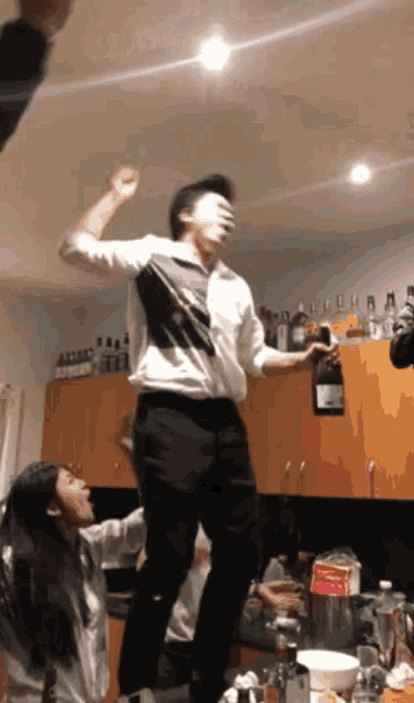 a man in a white shirt is dancing in a kitchen with a woman