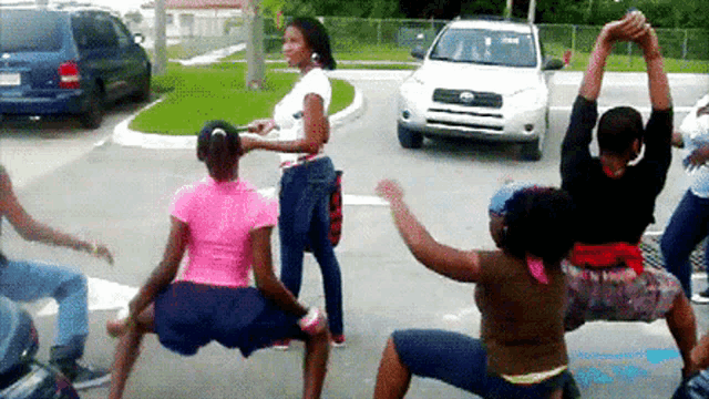 a group of people are dancing in a parking lot in front of a toyota suv