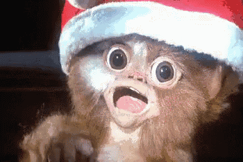 a close up of a gizmo wearing a santa hat with its mouth open .