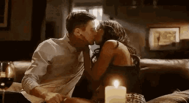 a man and a woman are kissing on a couch with a candle .