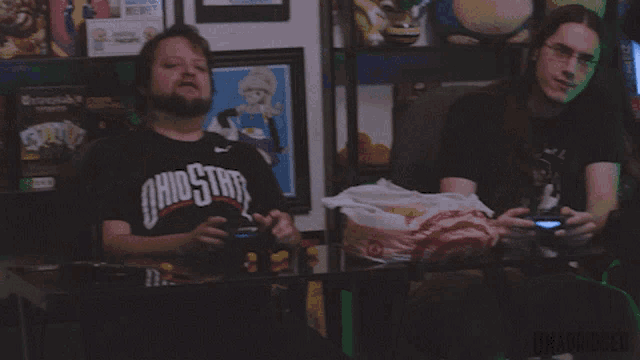 a man wearing a ohio state shirt is sitting at a table