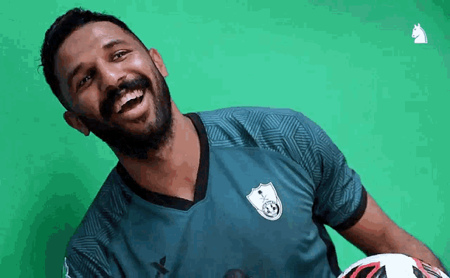 a man with a beard is holding a soccer ball and smiling for the camera