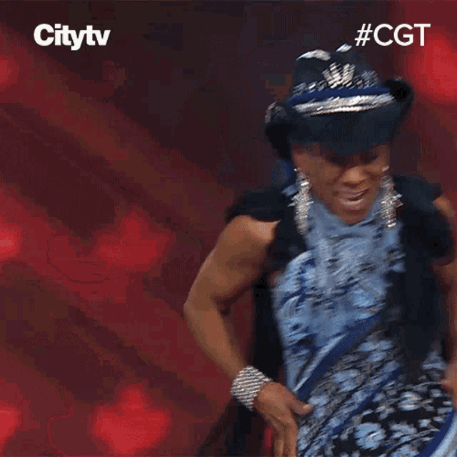 a woman wearing a cowboy hat and a blue dress is smiling in front of a sign that says citytv #cgt
