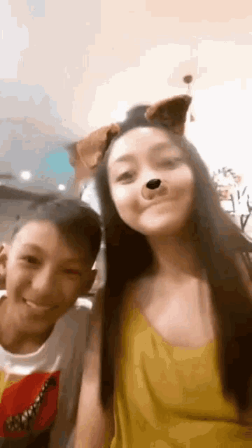 a boy and a girl are posing for a picture together . the girl is wearing a dog mask .
