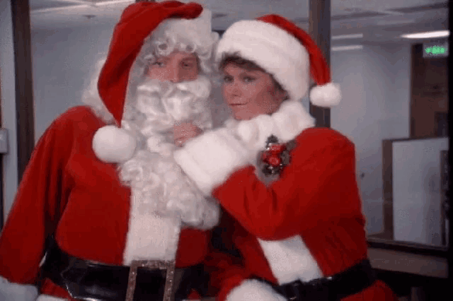 a man and a woman dressed in santa costumes