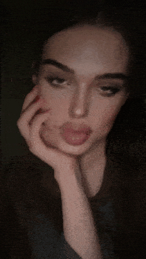a close up of a woman 's face with her hand on her chin