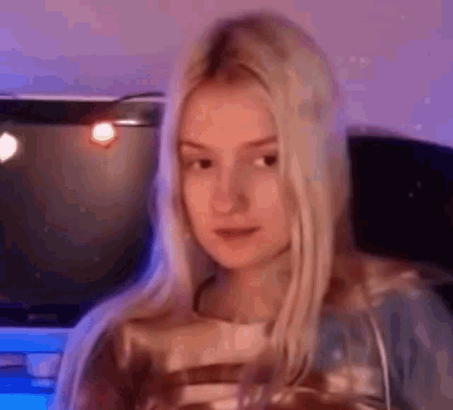 a young woman with long blonde hair is sitting in front of a computer .
