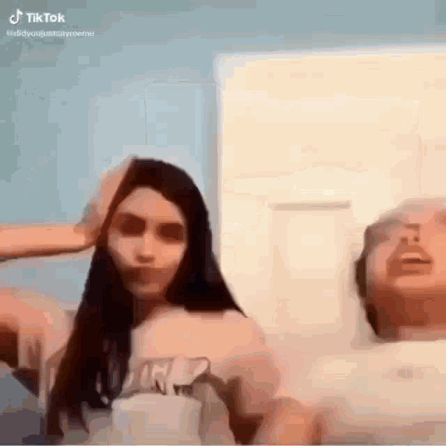 a man and a woman are sitting on a bed . the woman is holding the man 's head .