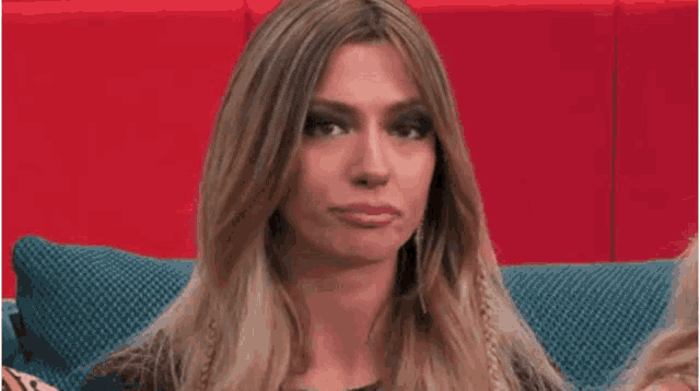 a woman is sitting on a blue couch with her eyes closed and making a funny face .