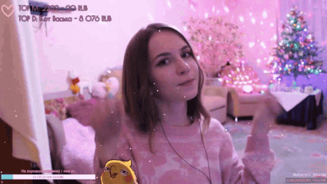 a girl in a pink sweater is looking at the camera