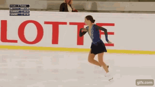 a woman is ice skating in front of a lotte sign