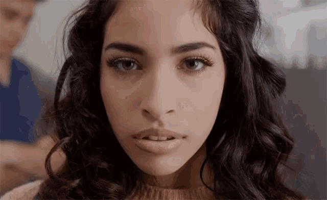 a woman with curly hair is looking at the camera