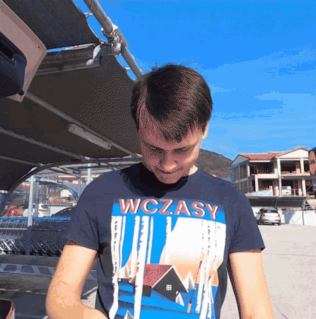 a man wearing a shirt that says wczasy looks down