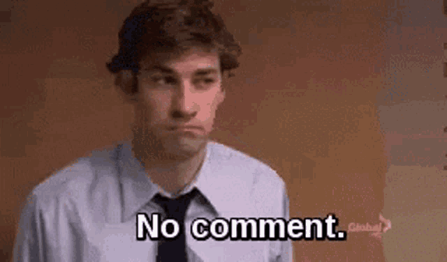 a man in a suit and tie is standing in front of a wall and saying `` no comment '' .