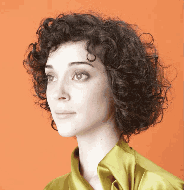 a woman with curly hair wearing a yellow shirt