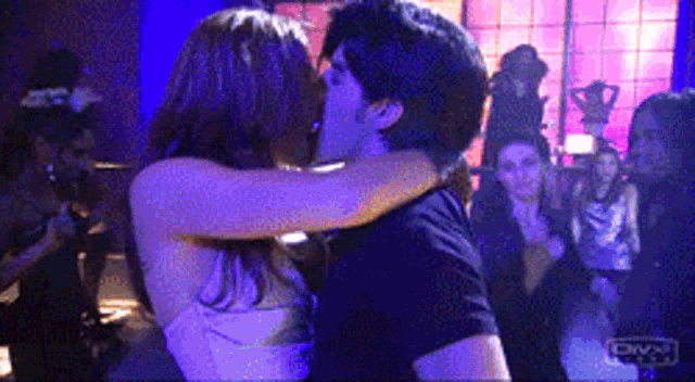 a man and a woman are kissing in a club with divx written on the bottom