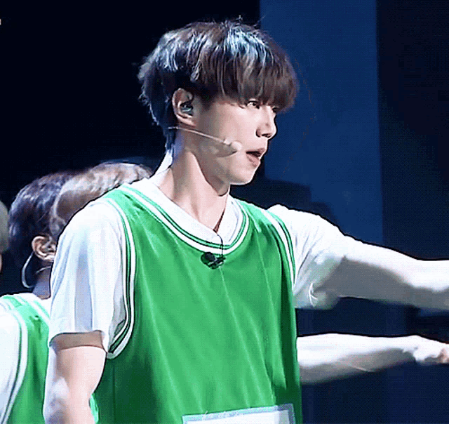 a man wearing a green basketball jersey and a microphone on his neck