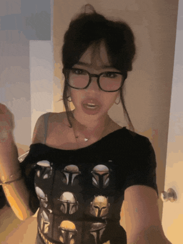 a woman wearing glasses and a mandalorian t-shirt takes a selfie