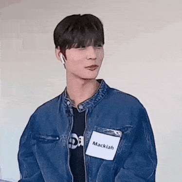 a young man wearing a denim jacket and a name tag with the name mackiah on it .