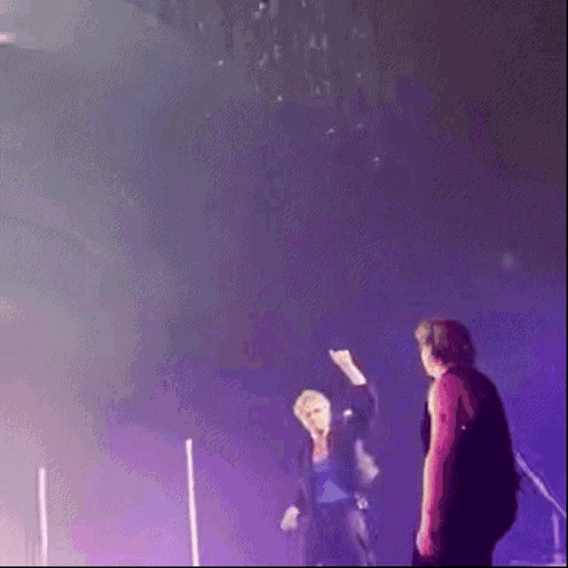 a man in a red jacket is standing next to a woman in a blue jacket on a stage .