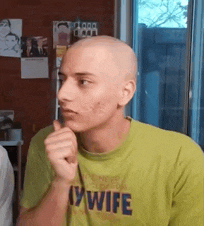 a man with a shaved head is wearing a green shirt that says `` i 'm a wife '' .