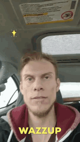 a man sitting in a car with the word wazzup on his face