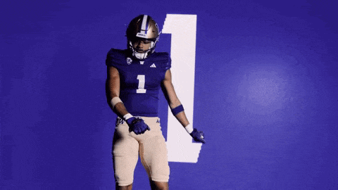 a football player in a purple uniform is dancing in front of a blue wall with the number 1 on it .