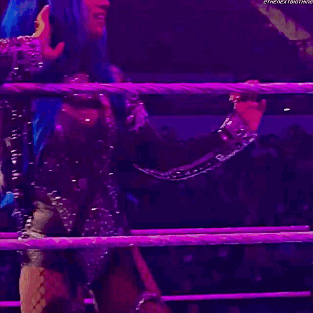 a woman with blue hair is standing in a wrestling ring ..