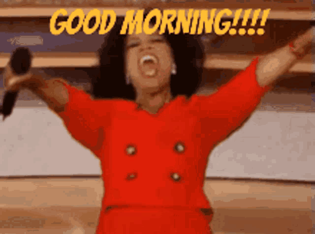 a woman in a red dress is holding a microphone with her arms outstretched and says good morning