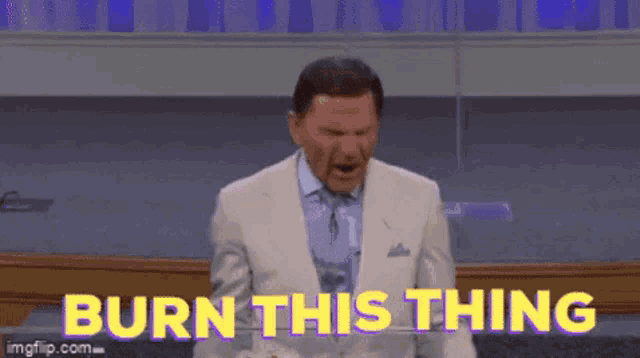 a man in a suit and tie is standing in front of a podium with the words `` burn this thing '' written on it .